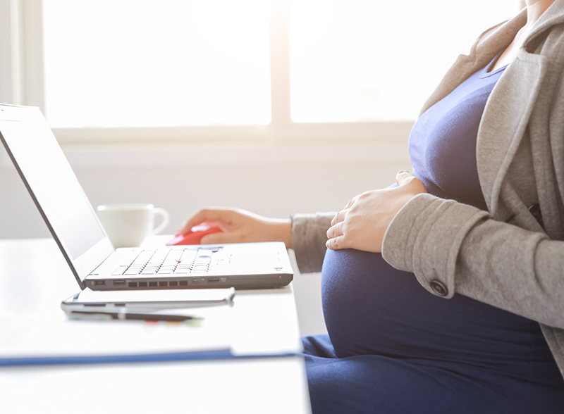 A pregnant worker uses a computer.